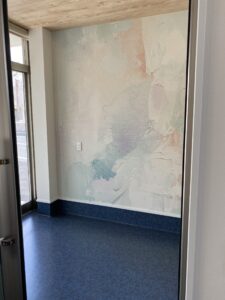 倉敷市クロキ動物病院のエントランス空間。デニム調の床と淡い色合いのアクセントクロスによるやわらかな内装デザイン。
