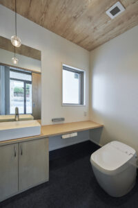 動物病院のトイレ空間。木目天井と造作洗面カウンター、デニム調床材を取り入れた内装デザイン。